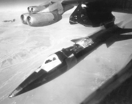 X-15 under wing of B-52 at moment of release with F-104 flying chase in the distance